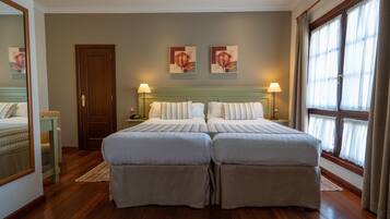 A double bed with a wooden headboard, a bedside table, and a lamp.
