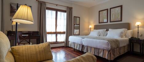 A hotel room with a bed, a desk, a chair, and a sofa.