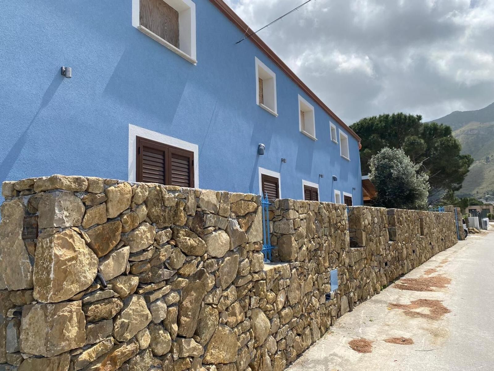 A two-story building with a stone wall and blue exterior.