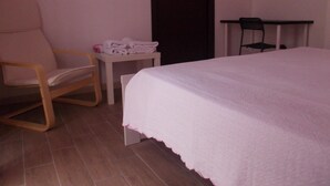 A hotel room with a bed, a chair, a small table with towels, and a desk. - B&B Pelagos (Castellammare del Golfo)