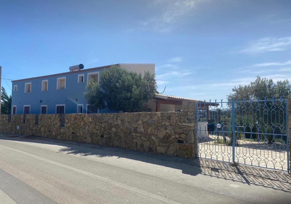 Un edificio de dos pisos con un muro de piedra y una reja metálica.