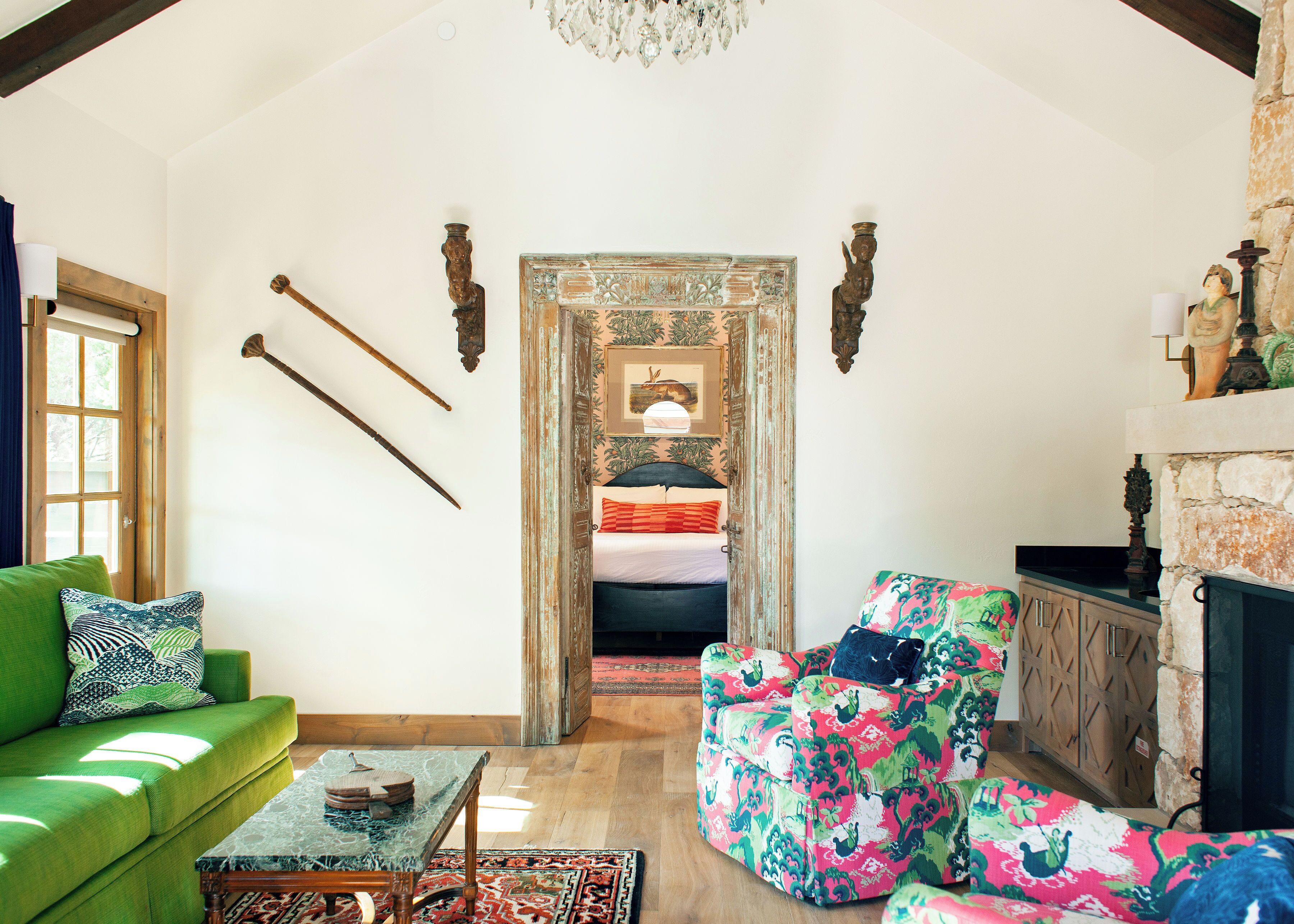 A cozy living room with a green sofa, a patterned armchair, a marble coffee table, and a fireplace.