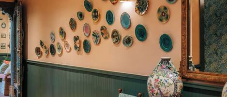 A wall with a collection of decorative plates and a large vase on a table.