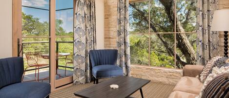 A room with a large window, a sofa, a chair, and a table.