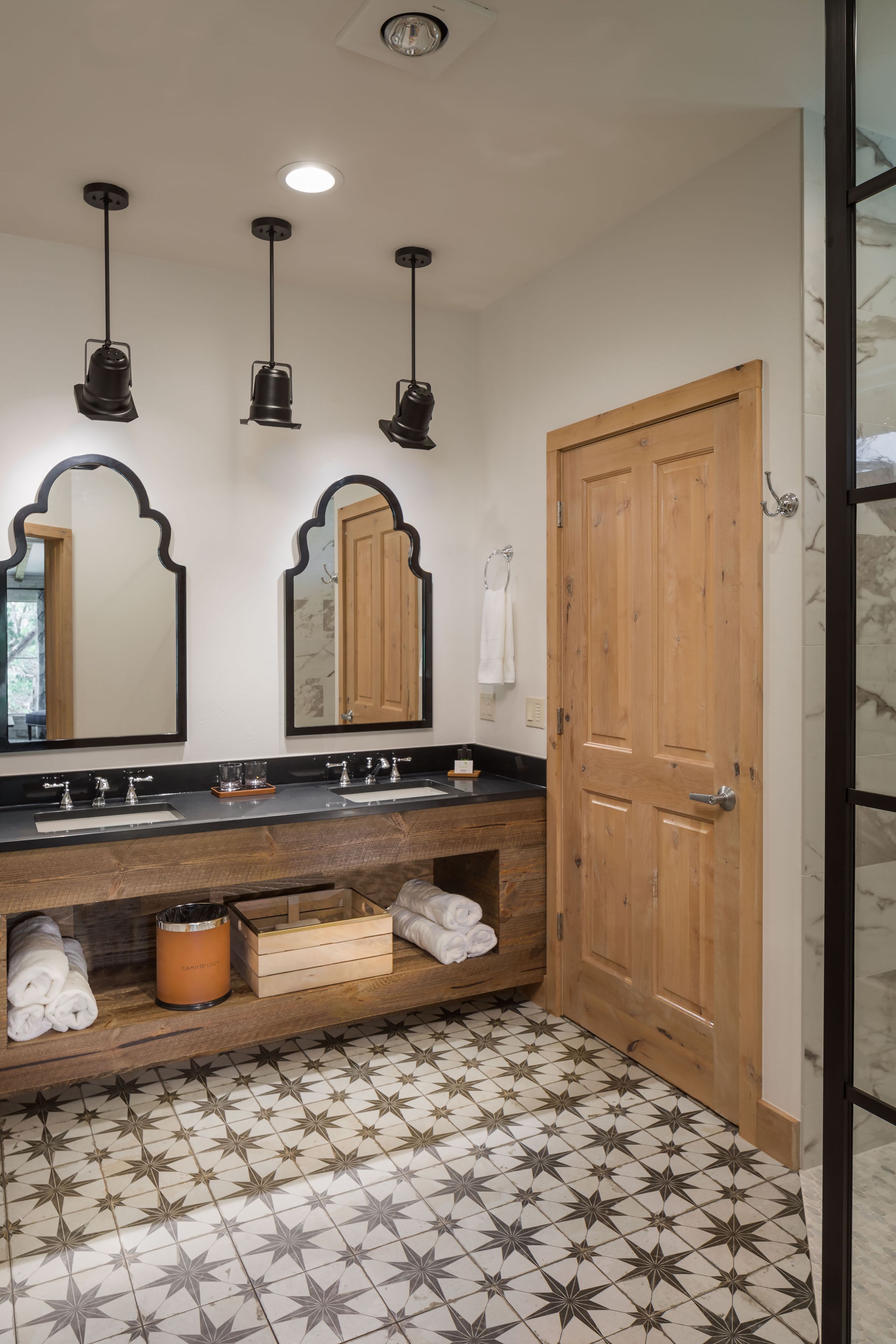 A bathroom with a wooden vanity, two sinks, a mirror, and a towel rack.