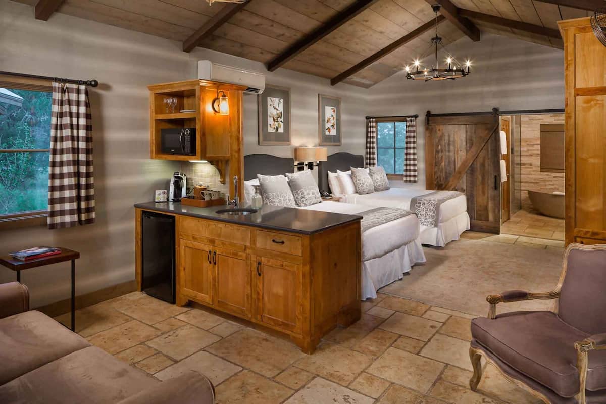 Ein gemütliches Schlafzimmer mit einem großen Bett, Holzmöbeln, einem Schreibtisch und Blick ins Freie.
