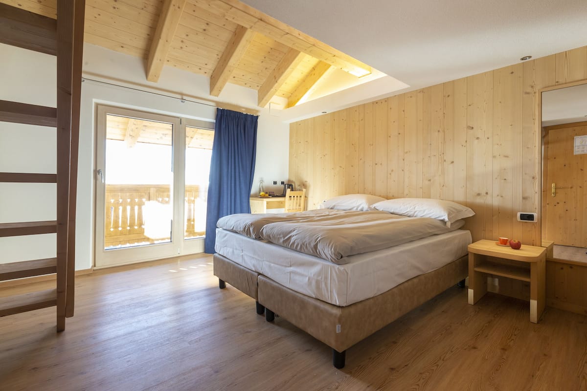 Habitación cuádruple | Edredón, minibar, caja de seguridad en la habitación y escritorio