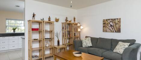 A living room with a grey sofa, wooden bookshelves, a wooden coffee table, and a ceiling fan.