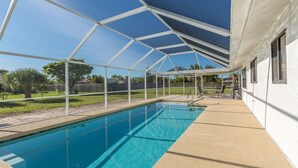 Une piscine dotée d’un espace couvert, avec une maison en arrière-plan.