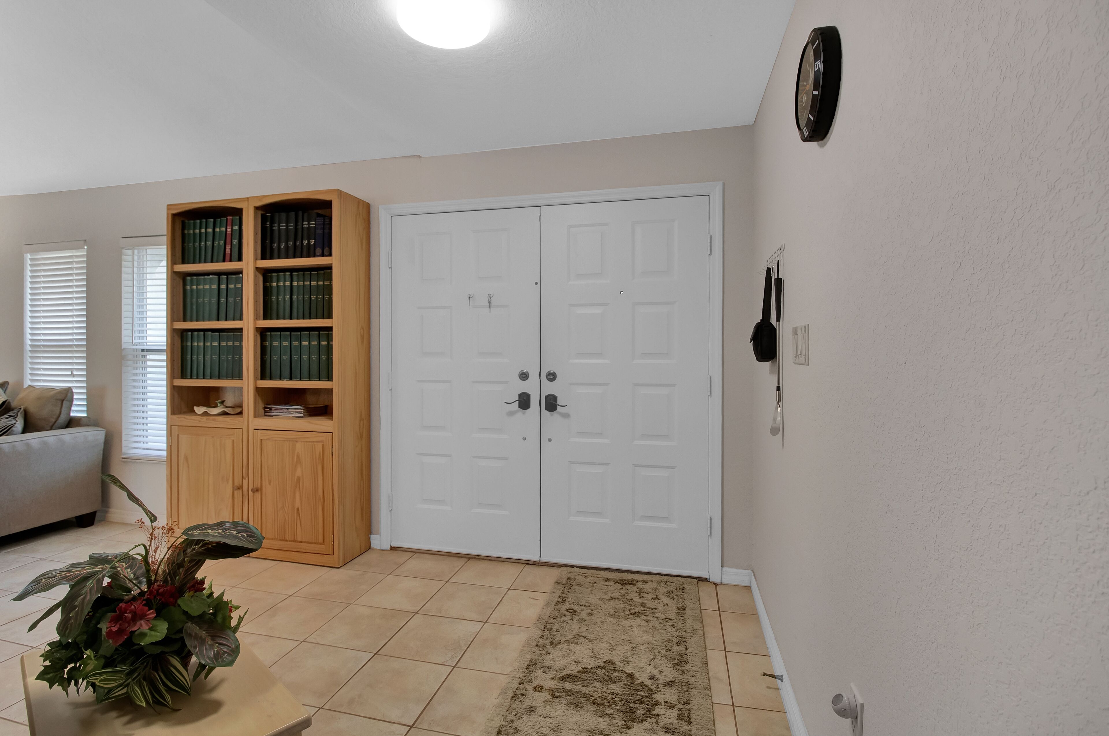 Una sala de estar con una estantería, una puerta blanca y un reloj en la pared.