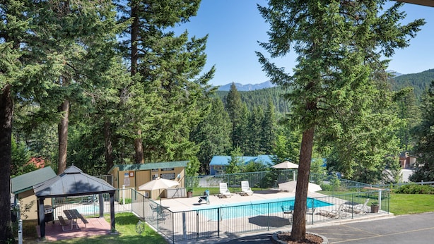 A pool area with lounge chairs, a gazebo, and a fenced deck. - Timbers Motel (Bigfork)