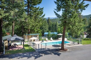 Un espace piscine comprenant des chaises longues, un gazebo et une terrasse entourée d’une clôture.
