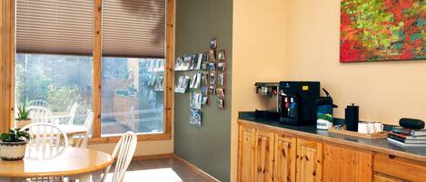 A kitchen with wooden cabinets, a coffee machine, and a dining area with a table and chairs.