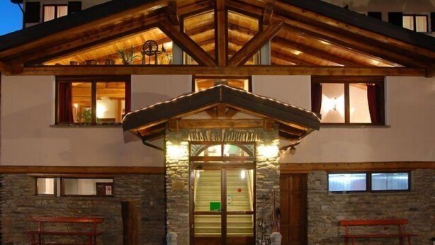 A two-story building with a stone facade, wooden beams, and a balcony. - Hotel Banchetta (Sestriere)