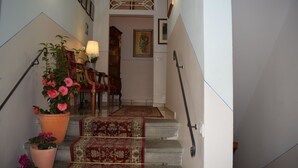 A staircase with a handrail, a red carpet, and potted plants. - Hotel Dalmazia (Florence)