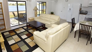 A living room with a sofa, coffee table, and dining area with chairs and a table. There is a large window with a view of a body of water. - Lilsis by the Lake - Vacation Home (Port Charlotte)