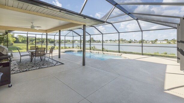 A covered patio with a pool, outdoor furniture, and a view of a lake. - Lilsis by the Lake - Vacation Home (Port Charlotte)