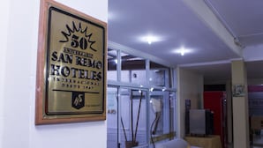 Un interior de hotel con un cartel enmarcado en la pared, un sofá blanco y un separador de vidrio.