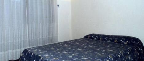 A room with a bed, a curtain, and a wall.
