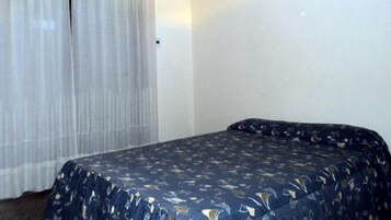 Una habitación con una cama, una cortina y una pared.