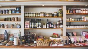 Een winkel met planken vol olijfolie, wijn en andere levensmiddelen.