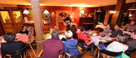 Un restaurant chaleureux, avec des meubles en bois et un pianiste qui joue.