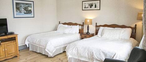 Une chambre d’hôtel avec deux lits simples, une armoire en bois, une télévision et deux lampes fixées au mur.