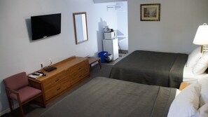 A hotel room with a bed, a desk with a chair, a television, a dresser, a microwave, and a painting on the wall. - Robyn's Motel (Otonabee-South Monaghan)