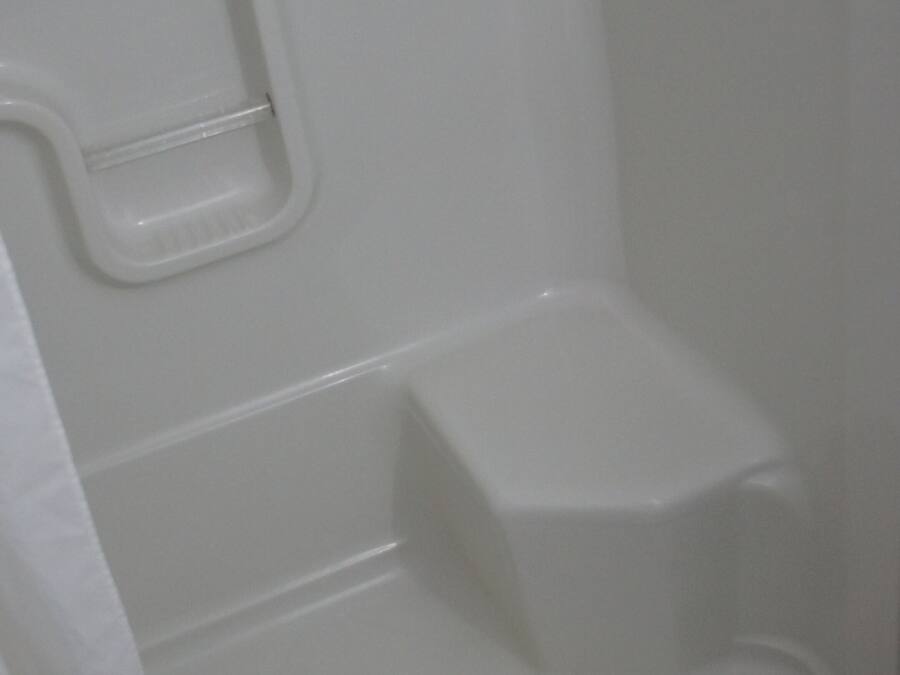 A bathroom with a shower area, a toilet, and a drain.