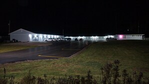 Un edificio con varios espacios de estacionamiento y un área verde al frente.