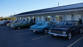 A row of vintage cars parked in front of a motel with numbered doors.