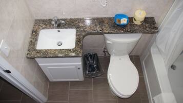Une salle de bain avec un lavabo à vasque en granit, des toilettes et une poubelle.
