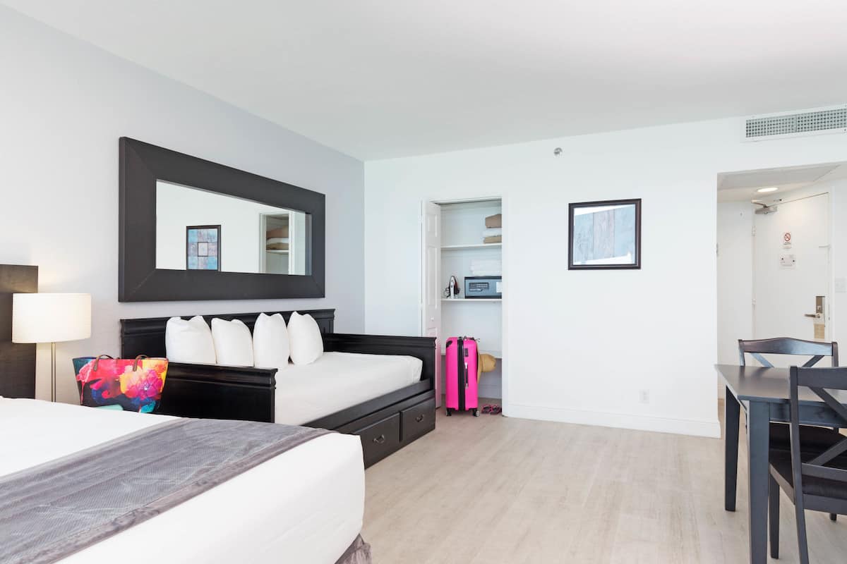 A hotel room with a bed, bedside table, lamp, and a desk with a chair.