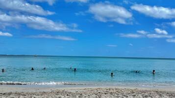 A beach with clear blue water and a sandy shore.