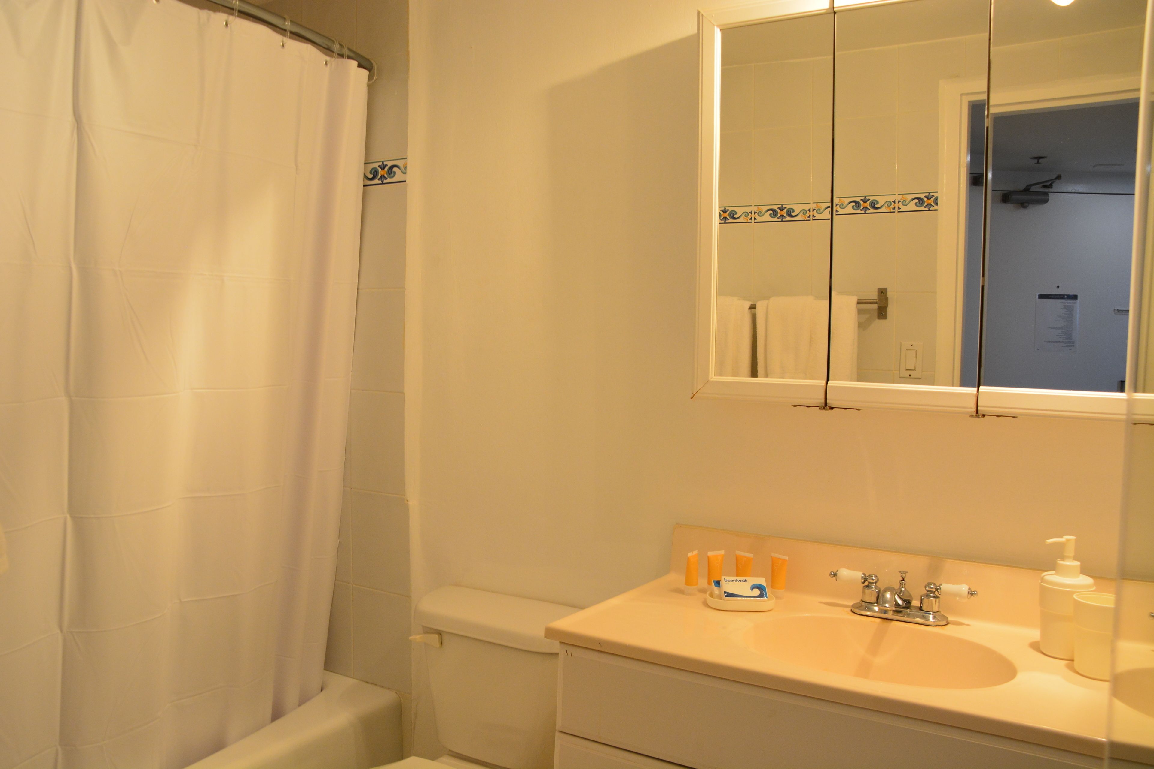 Un baño con lavamanos blanco, espejo y cortina de ducha.