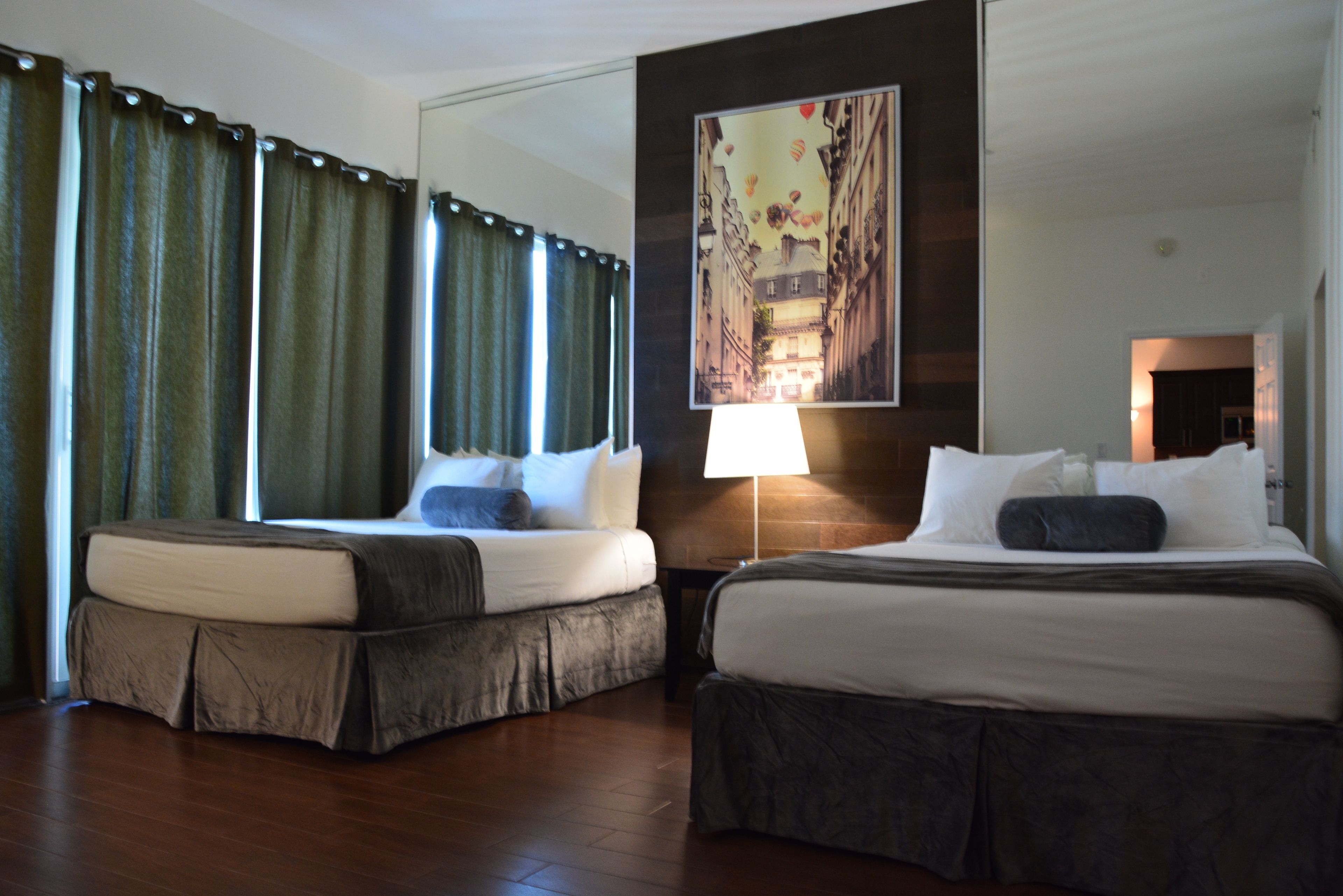 Habitación de hotel con dos camas, un espejo grande y un cuadro en la pared.