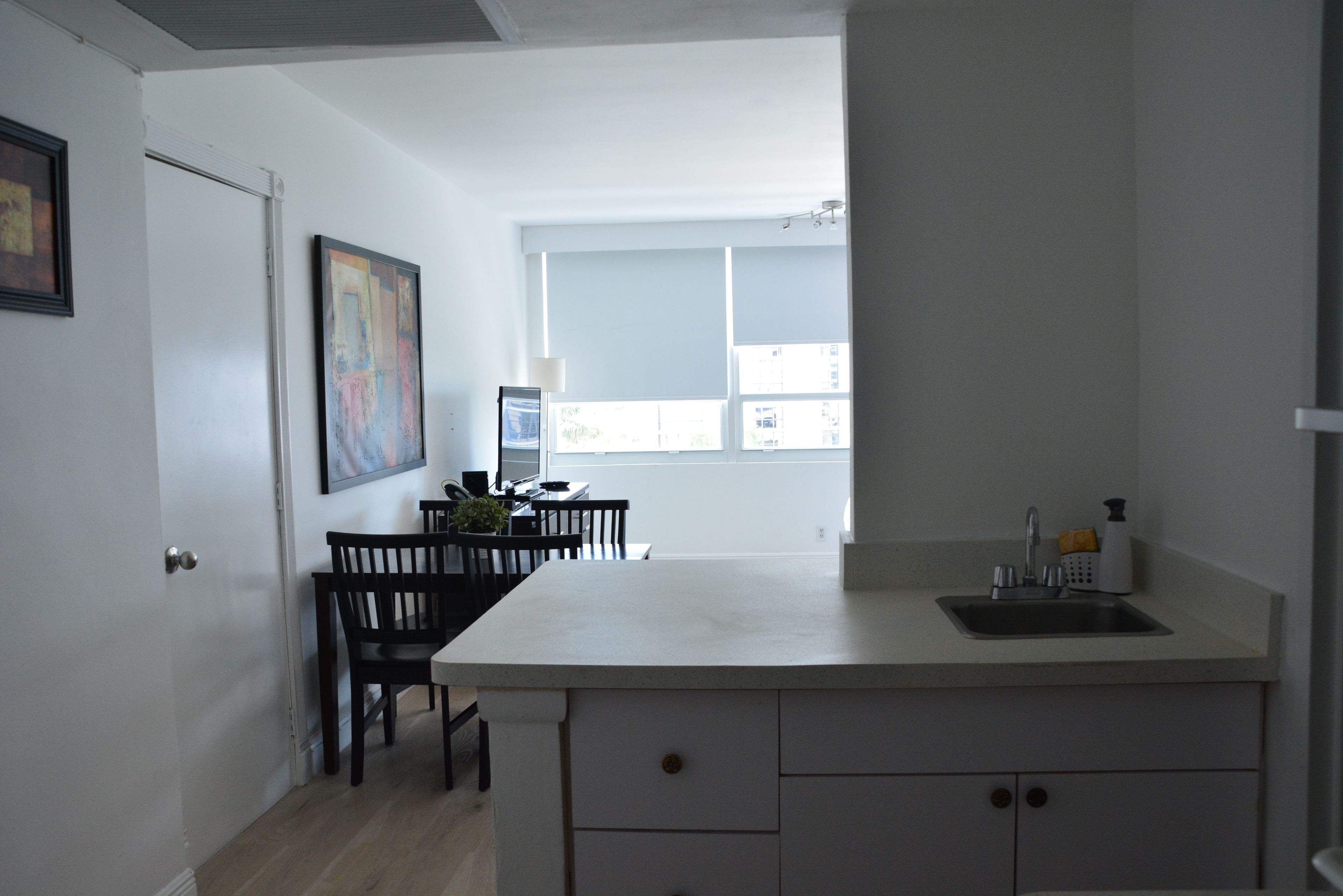 Une cuisine moderne avec un plan de travail blanc, un évier et un coin repas comprenant des chaises et une table.