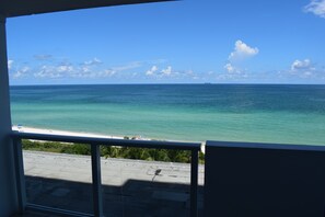 Vista de uma varanda sobre uma praia com águas azuis cristalinas e uma ilha ao longe.