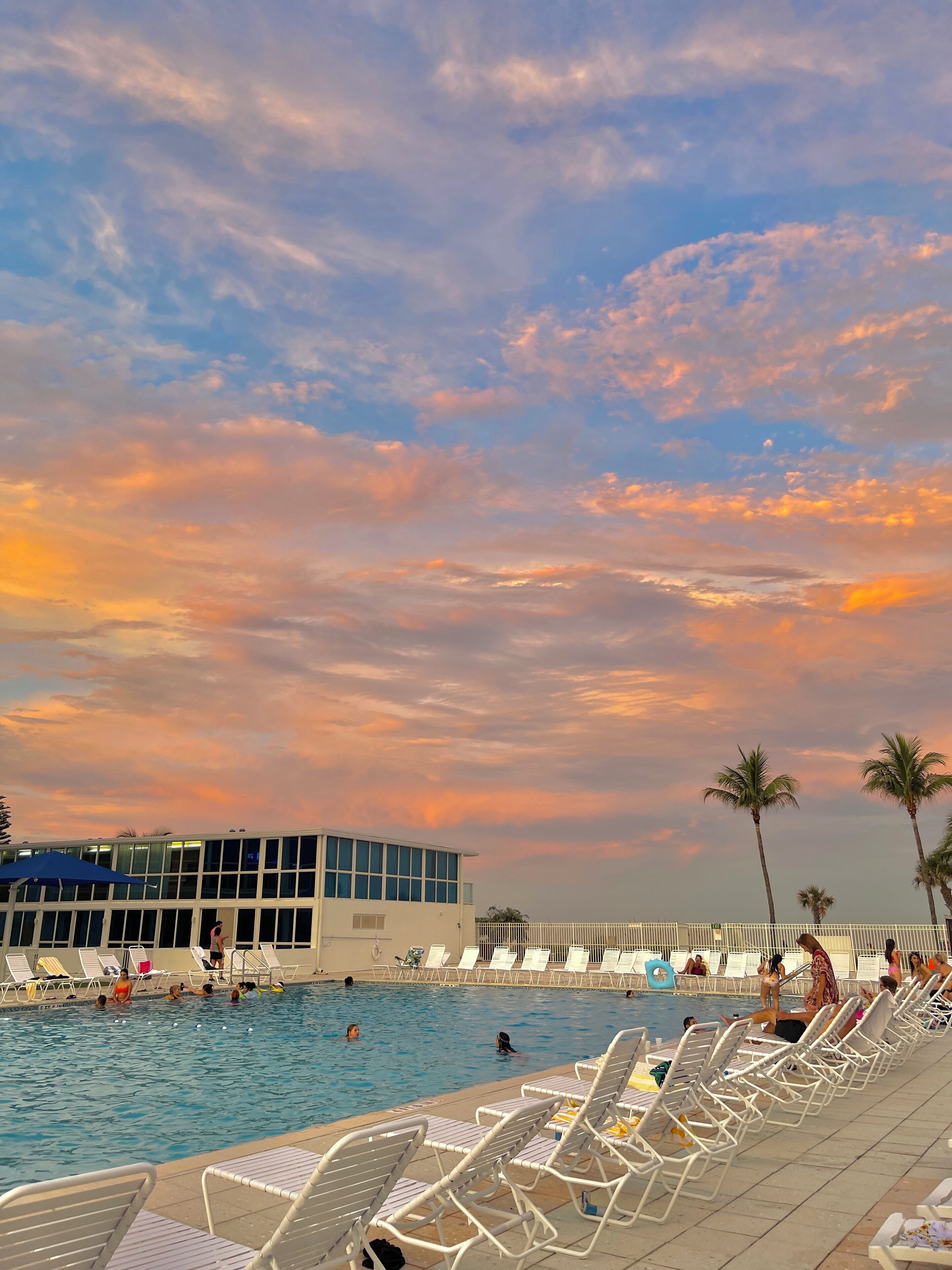 A swimming pool area with lounge chairs and a building in the background.