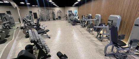 Un gimnasio moderno con diversos equipos de ejercicio, incluyendo mancuernas, cintas de correr y máquinas de pesas.