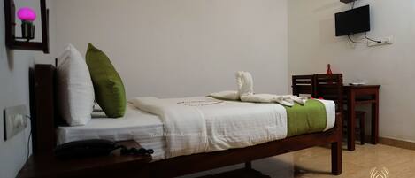 A neatly arranged bedroom with a bed, bedside table, and a desk with a chair.