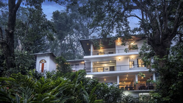 Una casa moderna de dos pisos rodeada de un bosque denso.