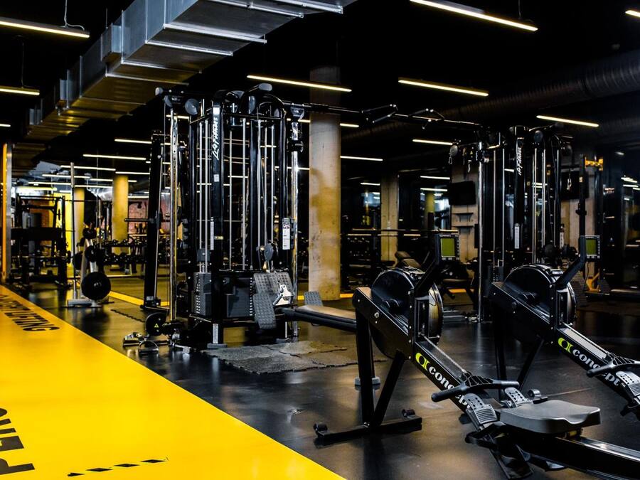 Un gimnasio con equipamiento de levantamiento de pesas y una línea de seguridad amarilla.