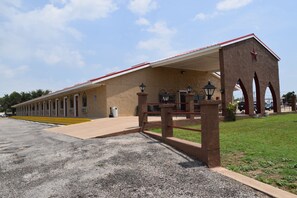 A long, single-story building with a red roof and beige walls, featuring a covered entrance with a red railing and a star on the roof.