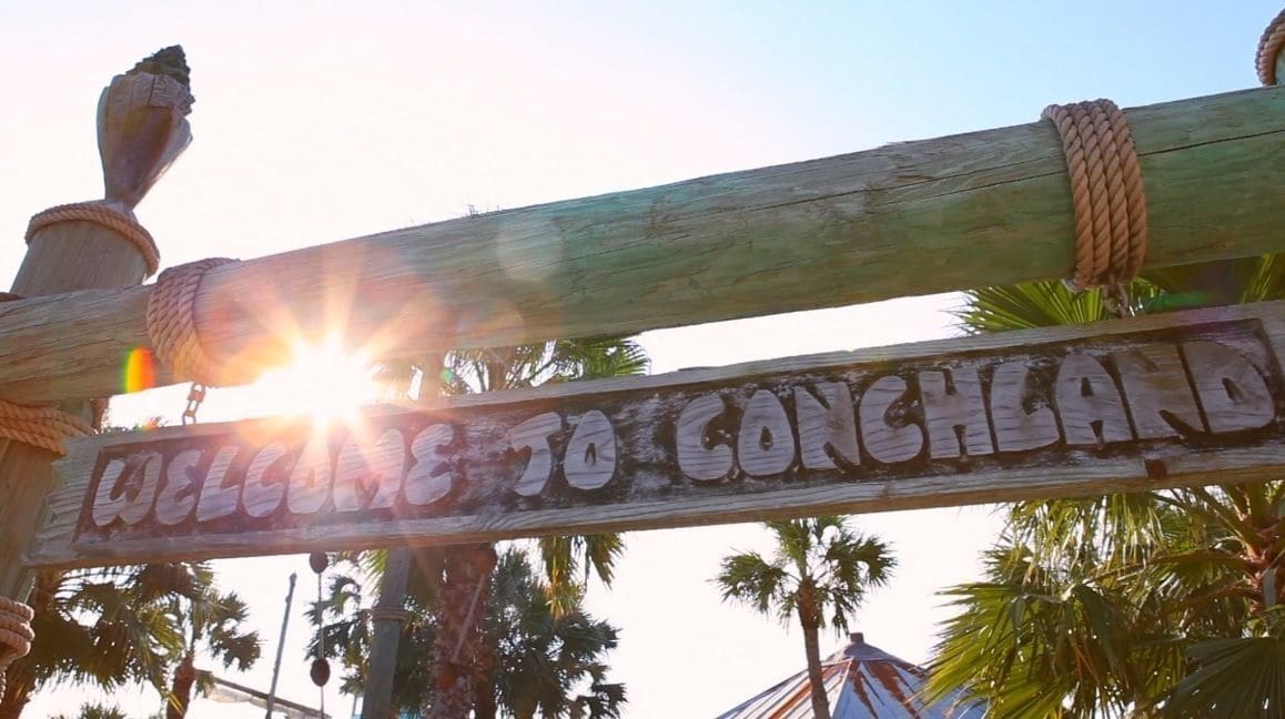 Une pancarte en bois portant l’inscription « BIENVENUE À CONCHLAND » et entourée d’une corde.