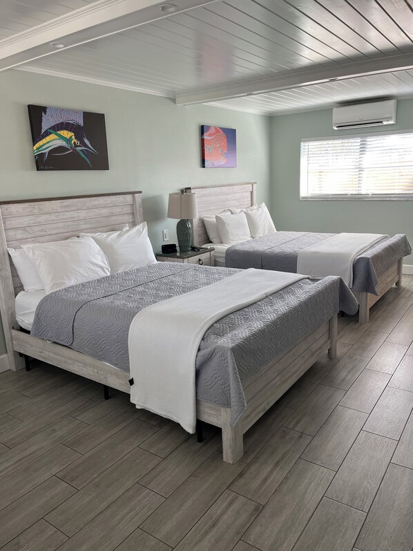 Una habitación de hotel con dos camas, una mesita de noche, una lámpara y cuadros en las paredes.