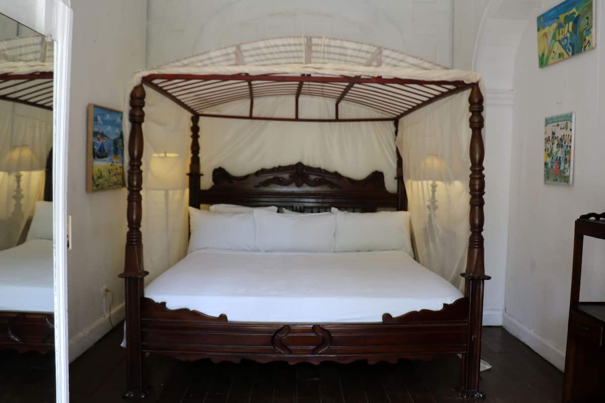 A four-poster canopy bed with a wooden frame and white linens.
