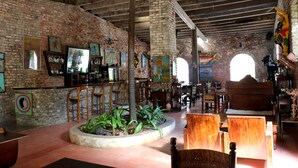 A spacious interior with exposed brick walls, wooden furniture, and a central planter with tropical plants.