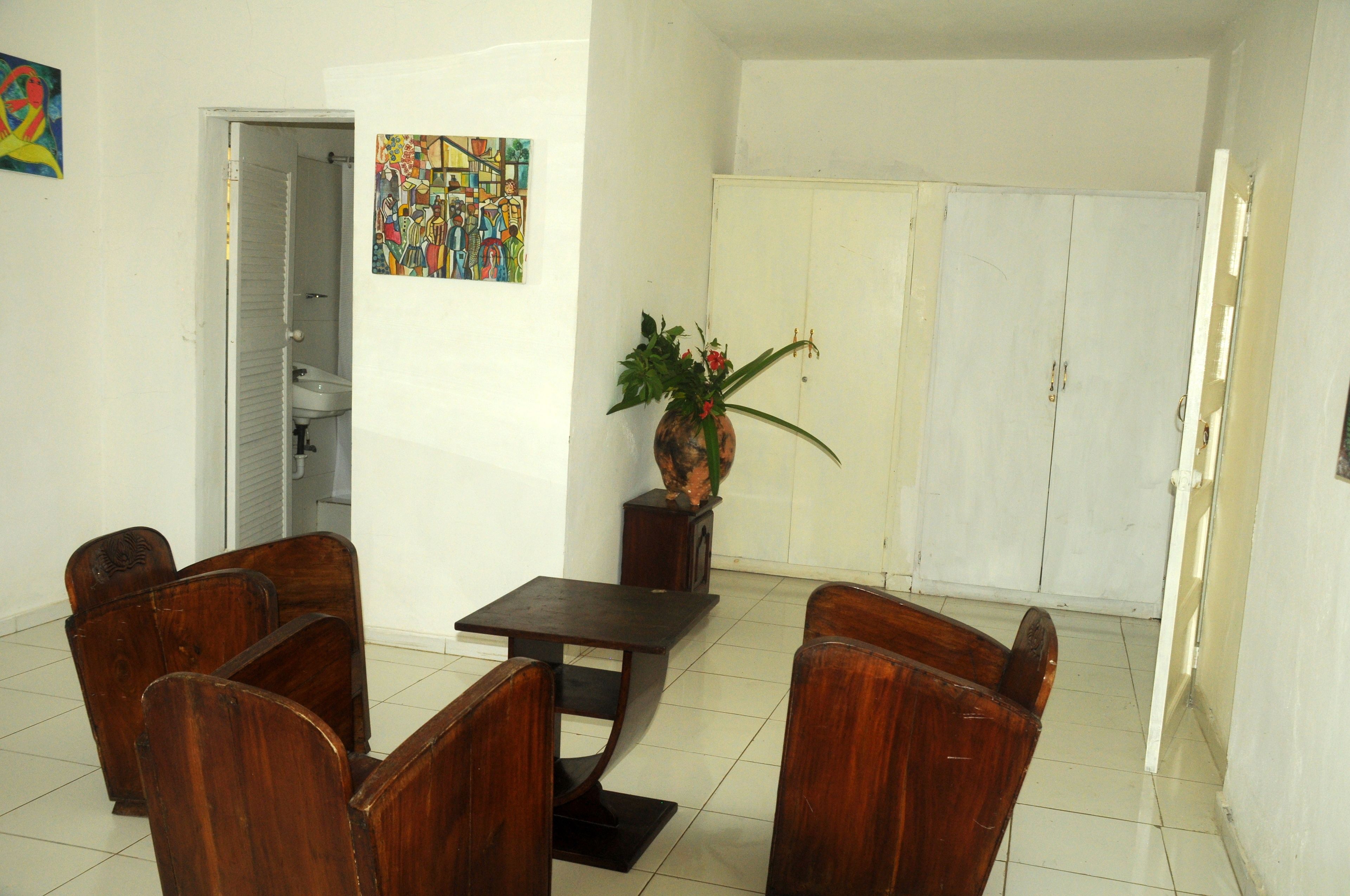 A dining area with wooden chairs and a table, a white cabinet, and a painting on the wall.