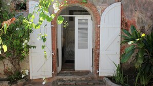 A rustic entrance with a brick archway and white shutters.